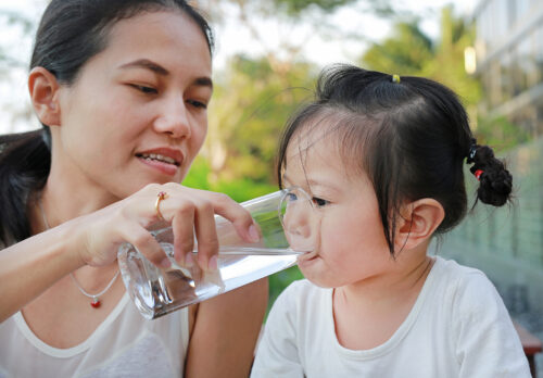 Mother giving glass of water to her child..