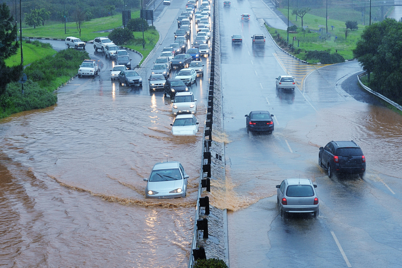 Motorists drive through water on a flooding highway